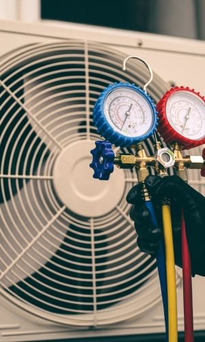 Plumber Holding Gauges Near Air Conditioning Unit